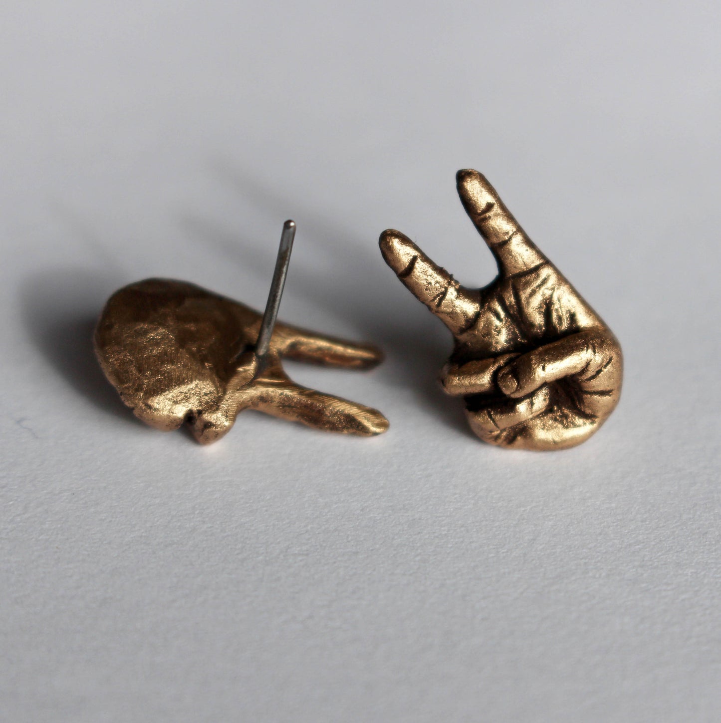 bronze and titanium earrings with hands making the victory sign