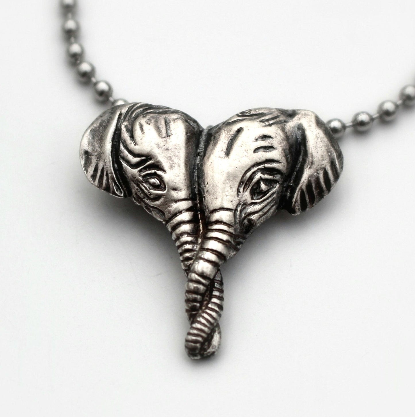 Silver necklace with a pendant featuring two elephant heads in a heart shape