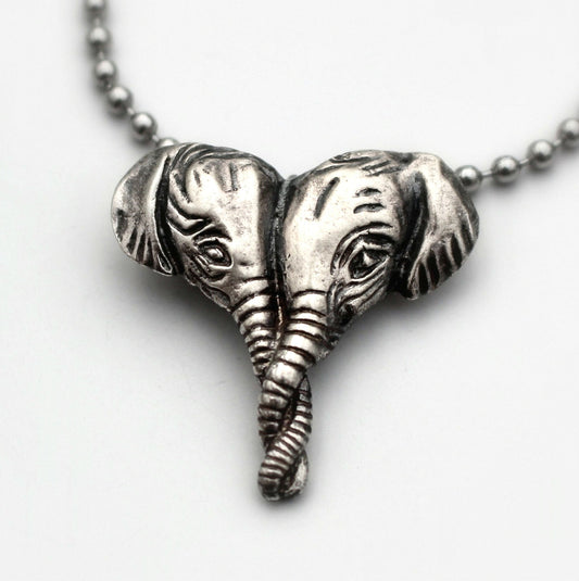Silver necklace with a pendant featuring two elephant heads in a heart shape