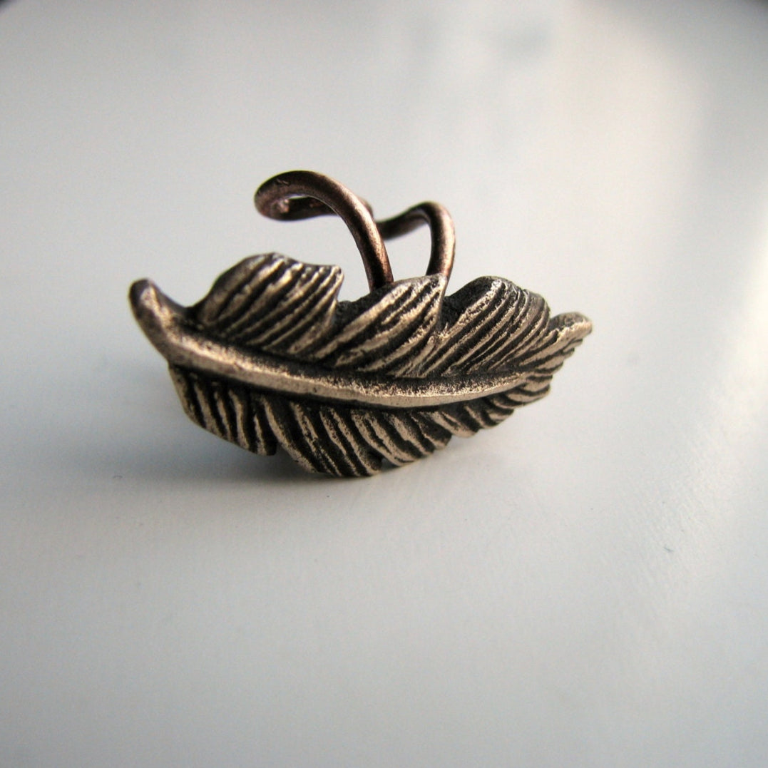 Bronze feather ear cuff on a light gray background