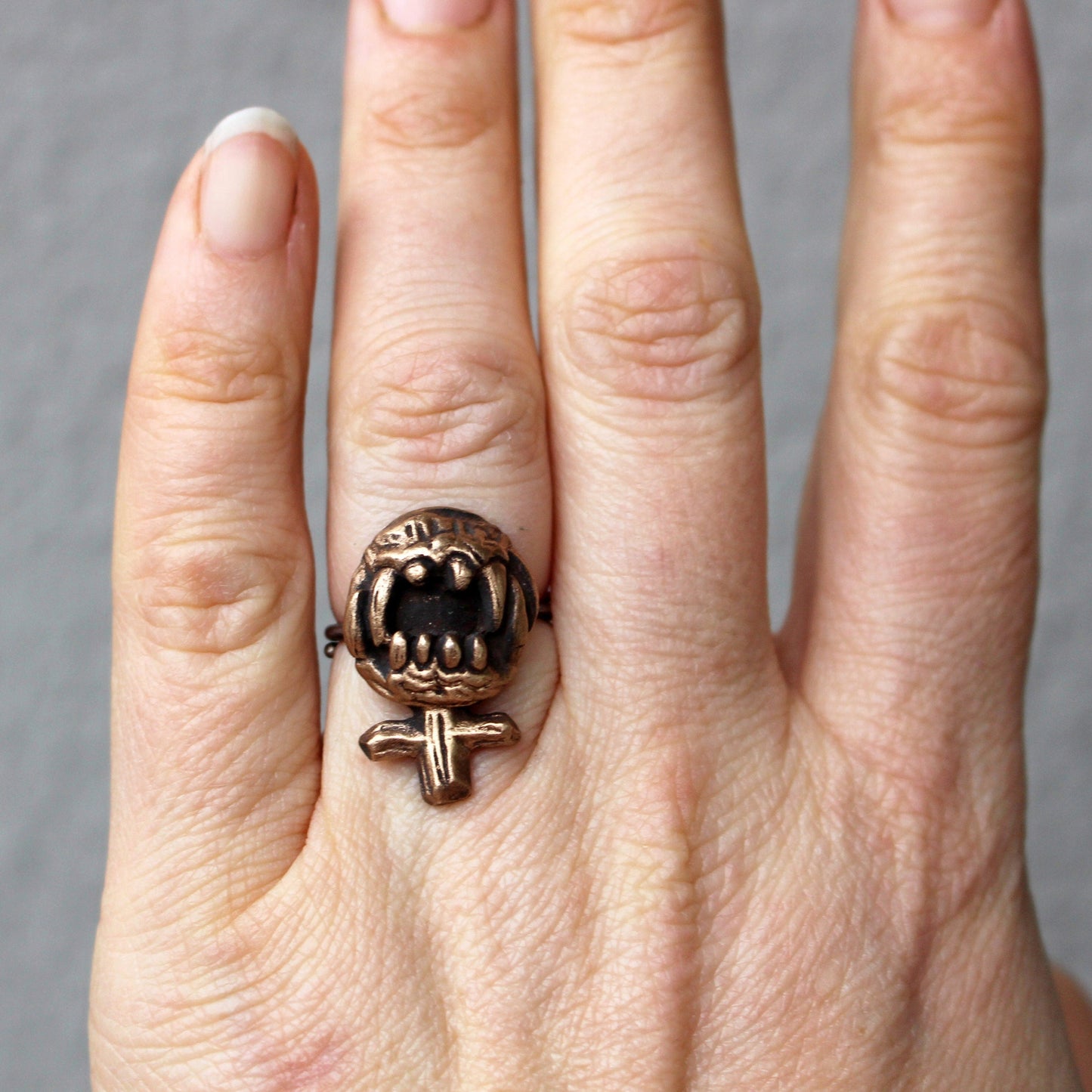 feministtecken skulpterad i brons med vassa tänder som fingerring