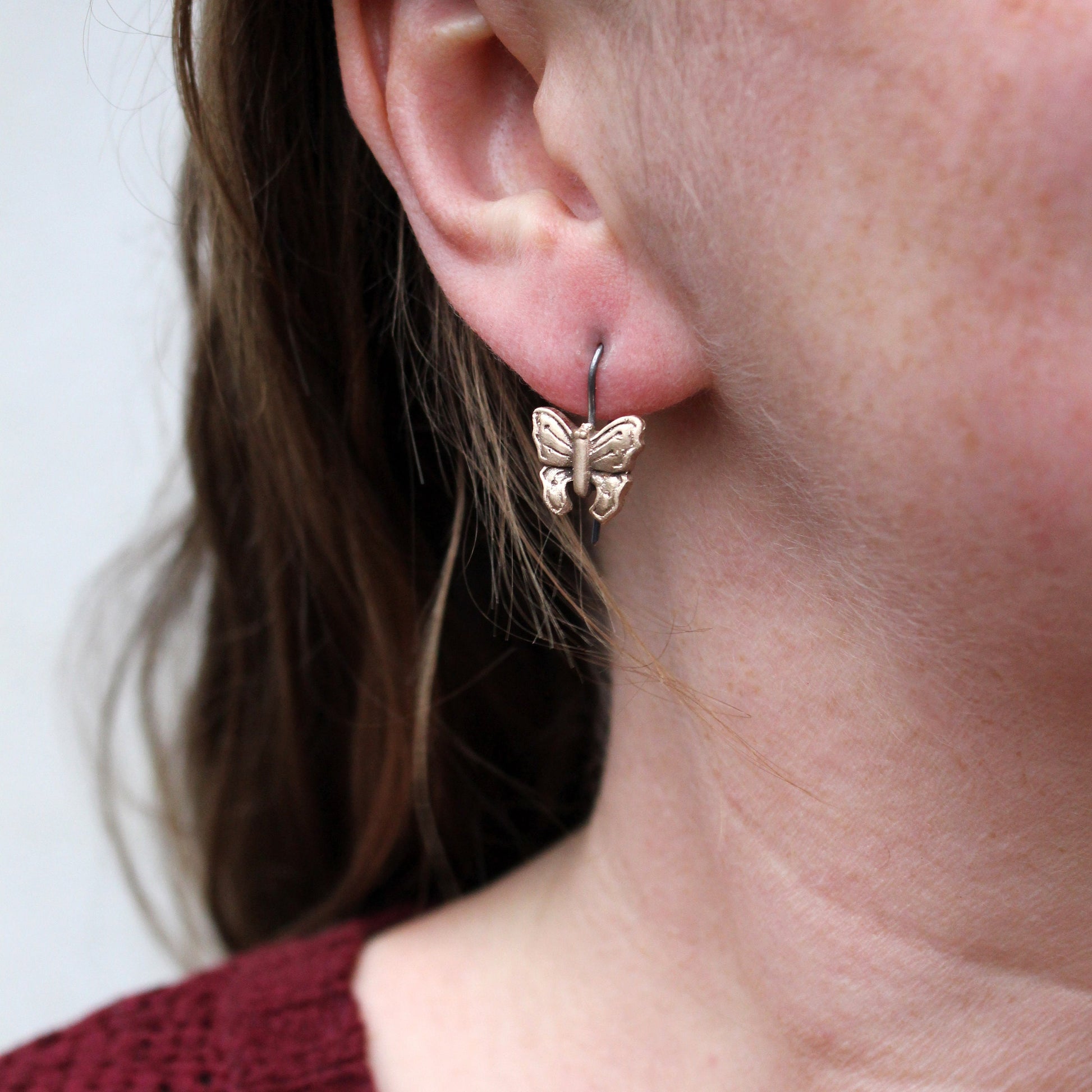 titanörhängen med skulpterade fjärilar