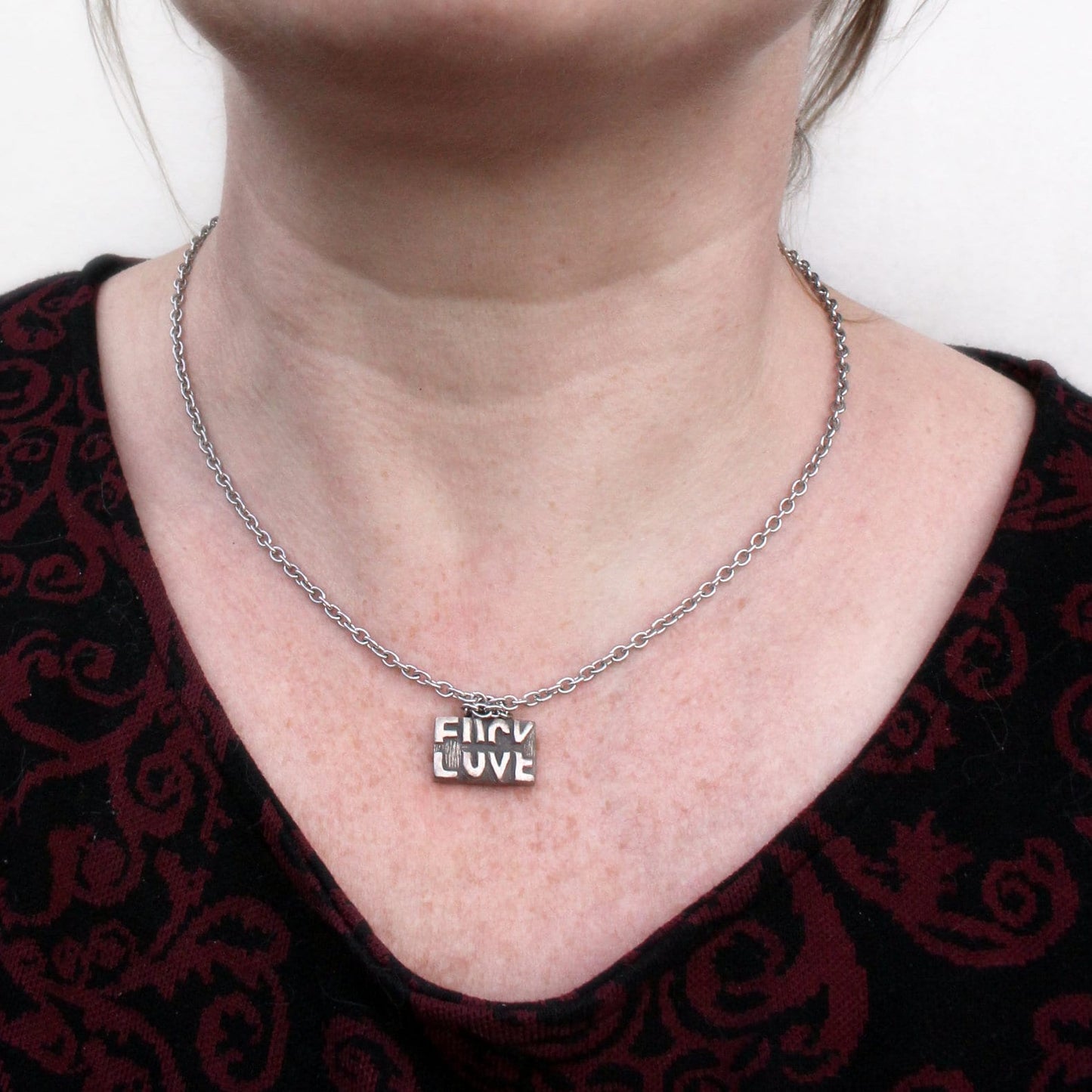 Halsband där det står fuck love beroende på hur den läses, rebus typografi bokstäver halsband