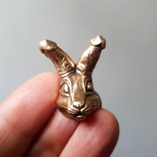 A unique handcrafted miniatyre bronze sculpture necklace depicting a surreal quirky bunny with penises for ears