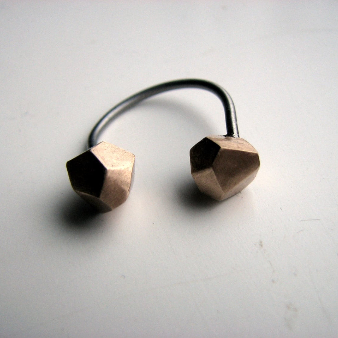 a geometric  ring with two bronze faceted cubes on each side of a steel ringband