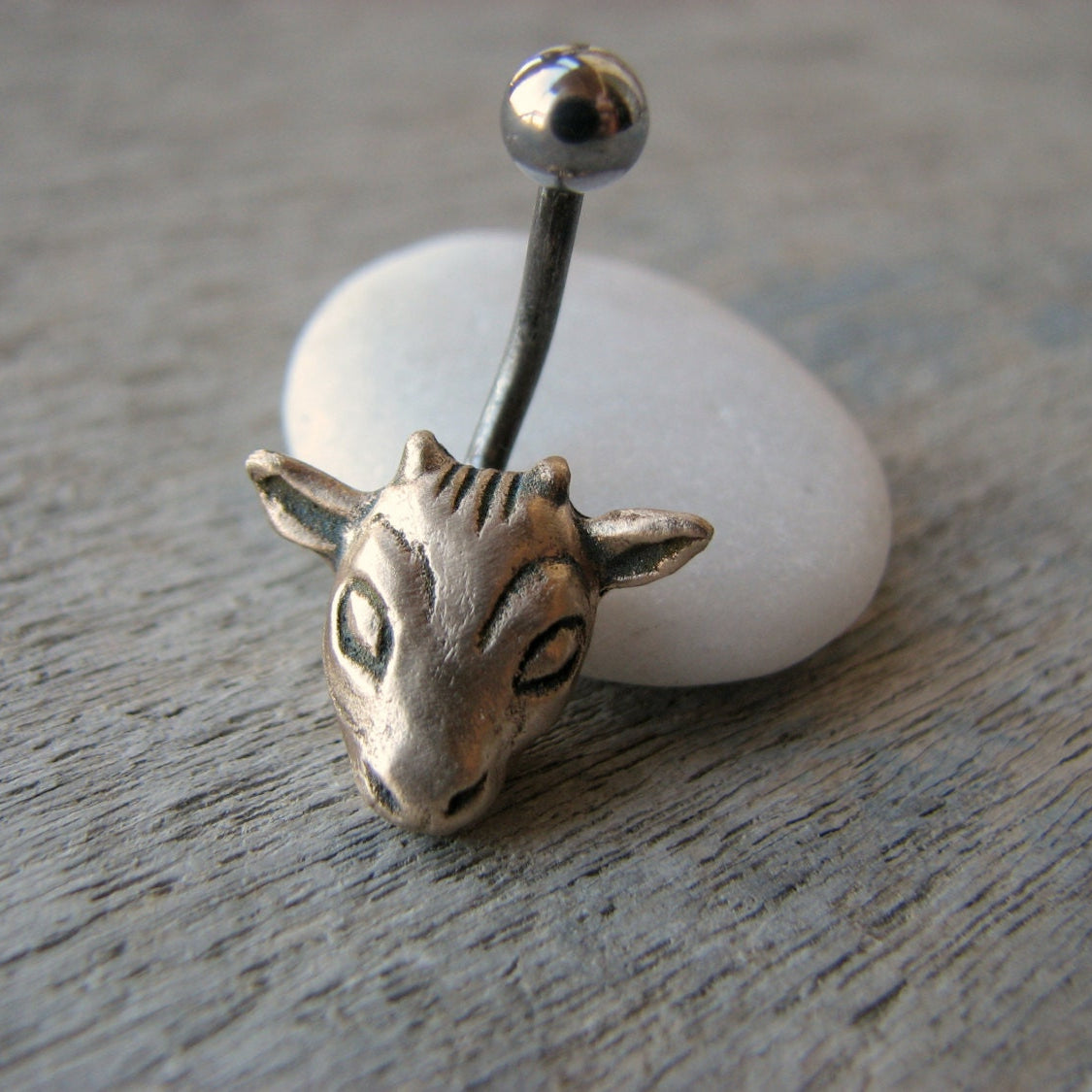 navelpiercingsmycke med ett gethuvud skulpterat i brons, stav i titan eller kirurgiskt stål
