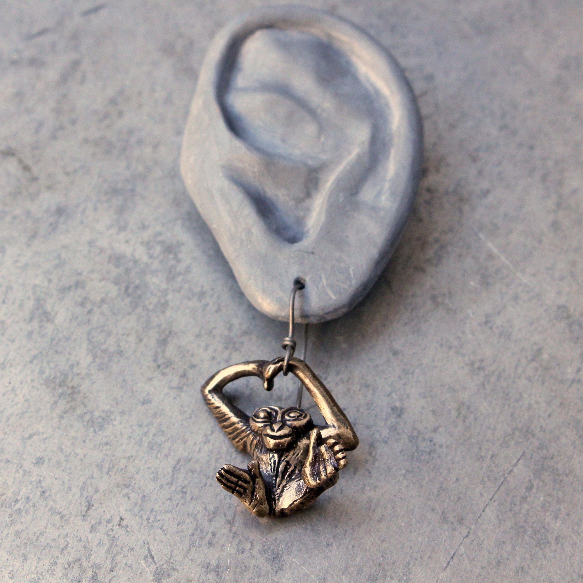 örhänge med gibbon apa skulpterad i brons, med krok av titan