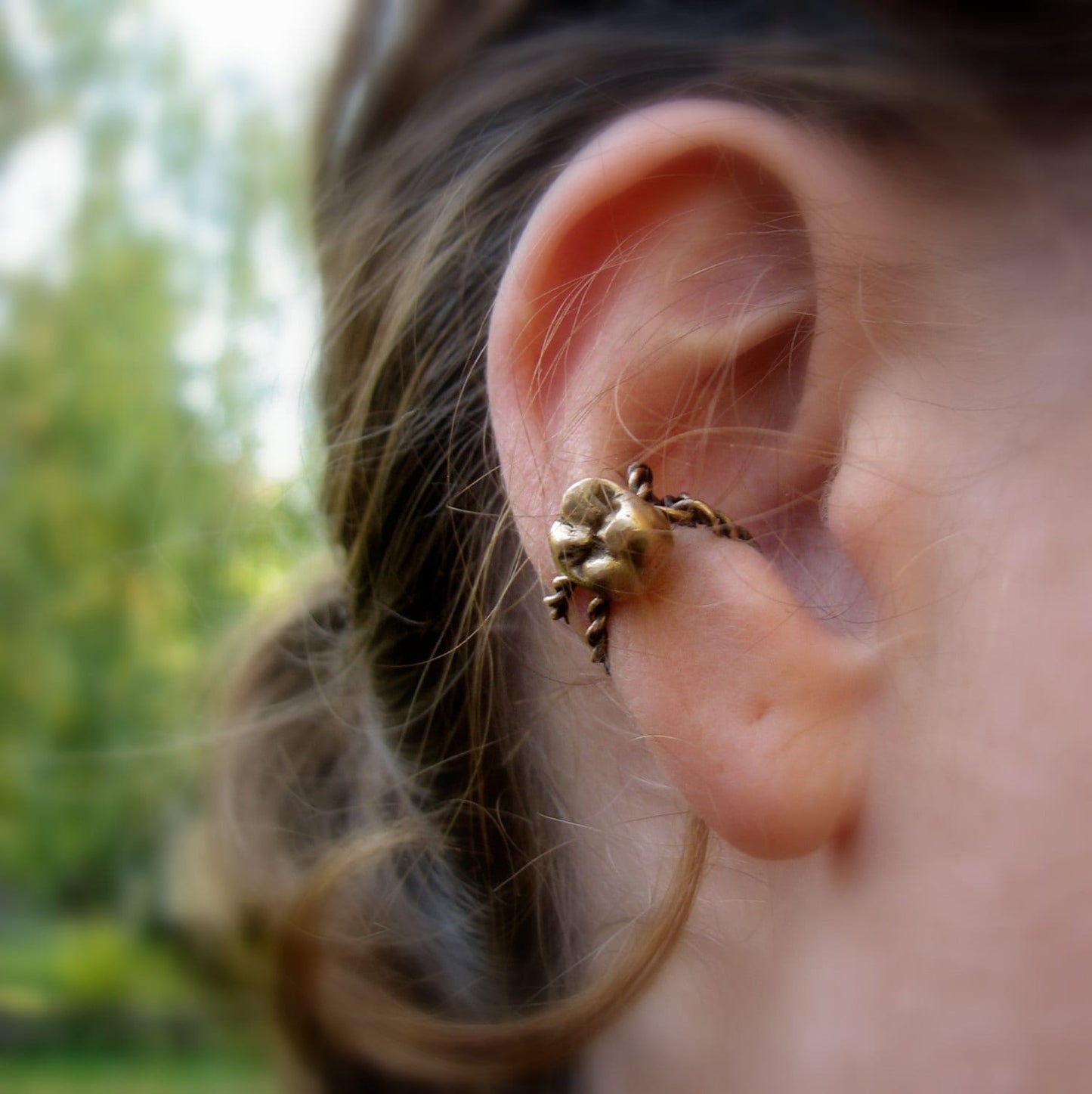 A person wearing a gold tooth ear cuff on their ear
