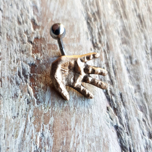 A belly button ring featuring a bronze human hand 