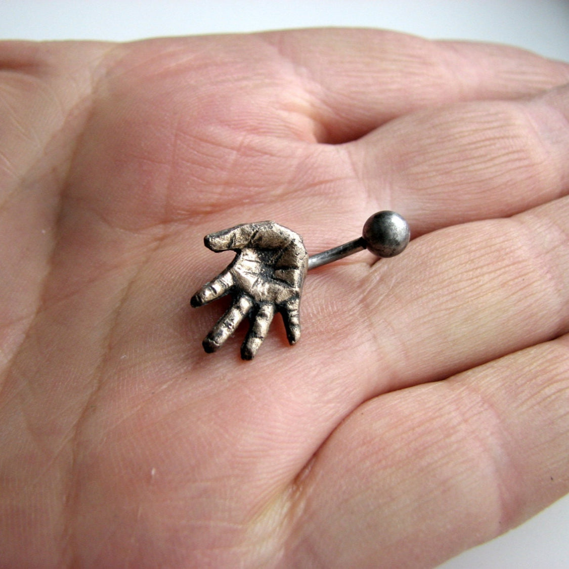 navel piercing smycke med en miniatyr hand