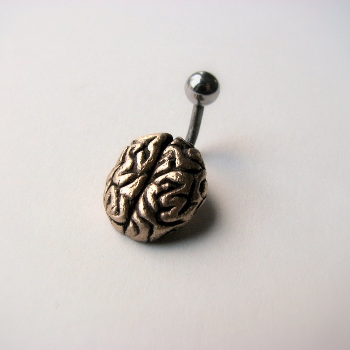 Navelpiercing smycke med en liten skulpterad hjärna i brons och titan stång