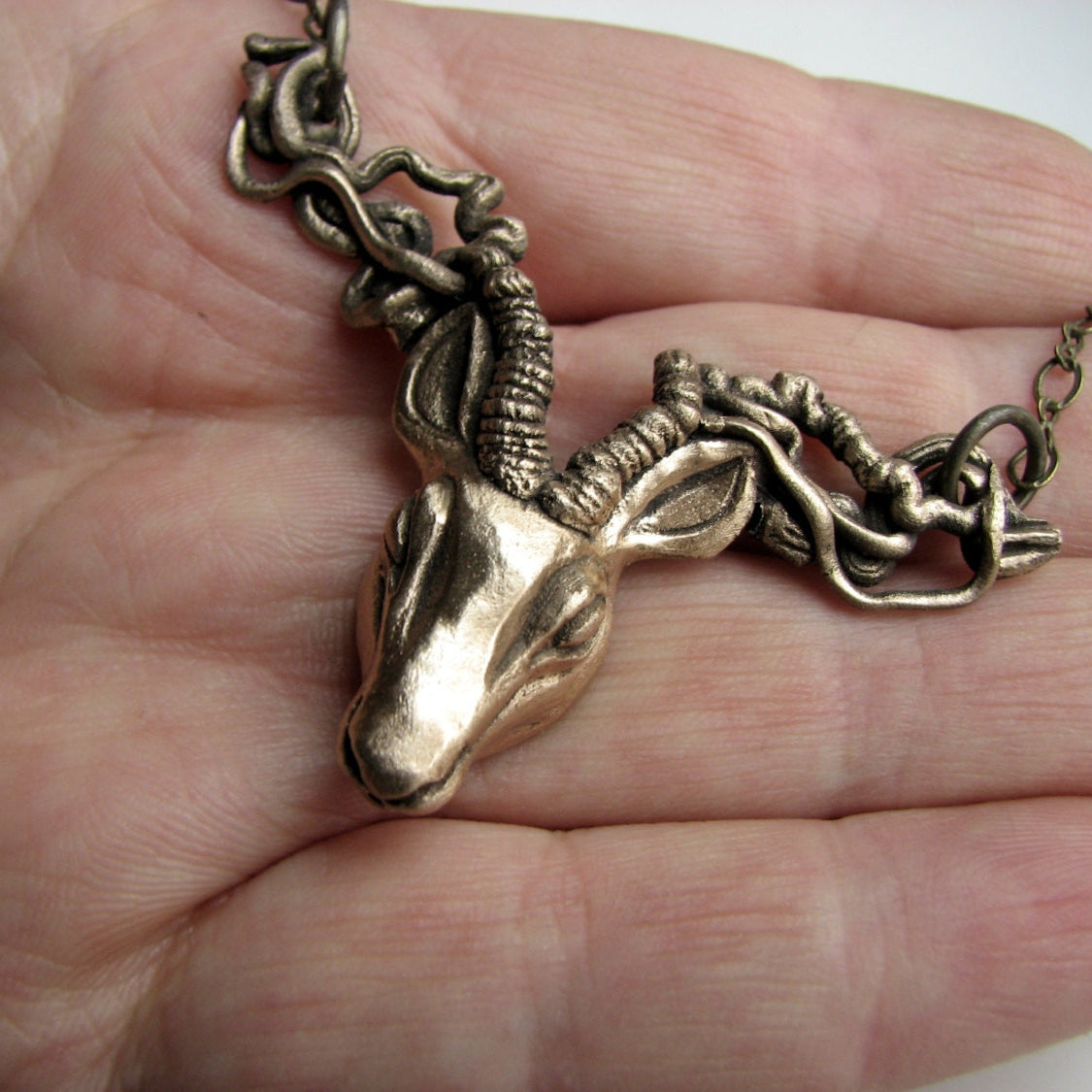 Halsband med en hjort eller rådjur i brons i en hand