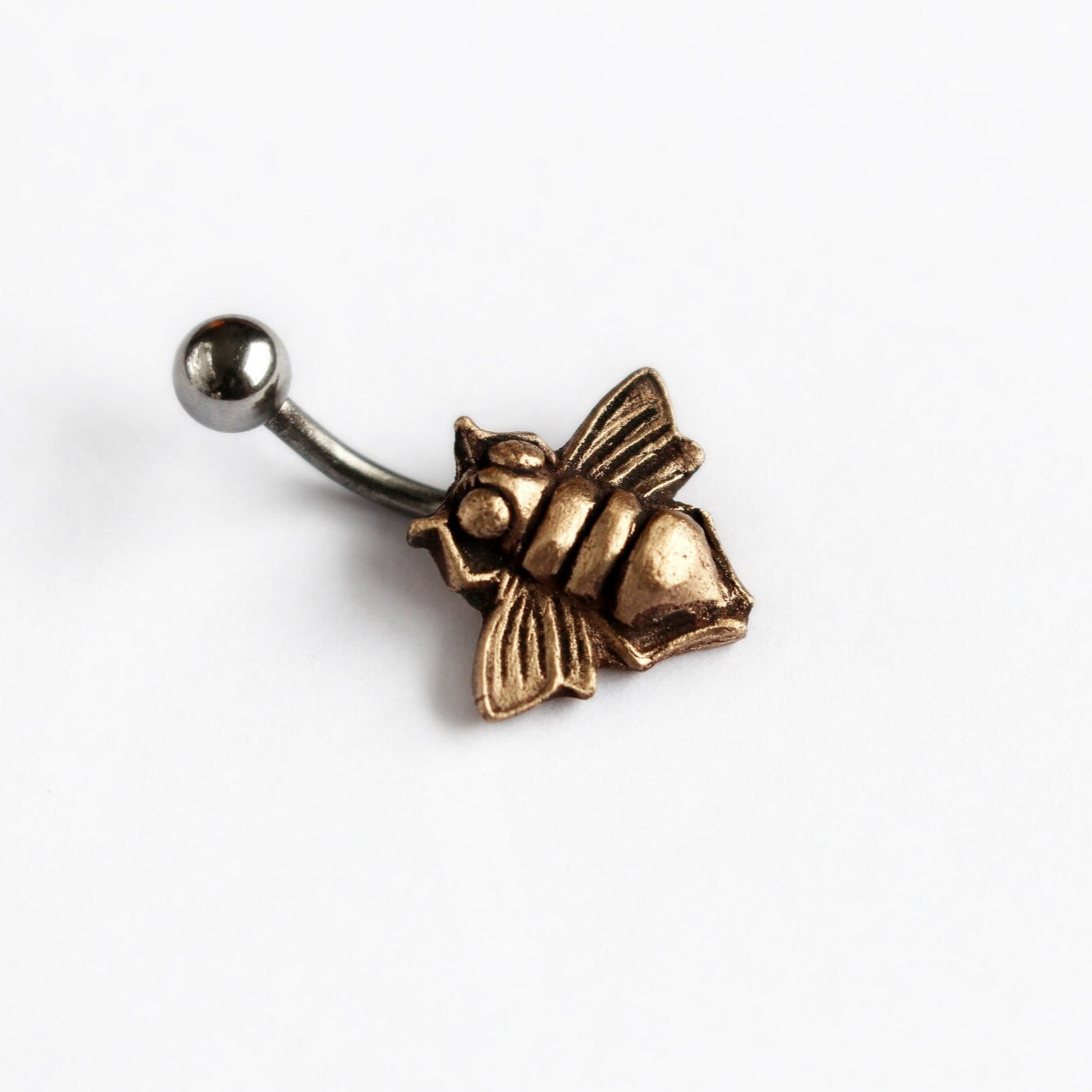 A bronze-colored belly button ring with a honey bee design.