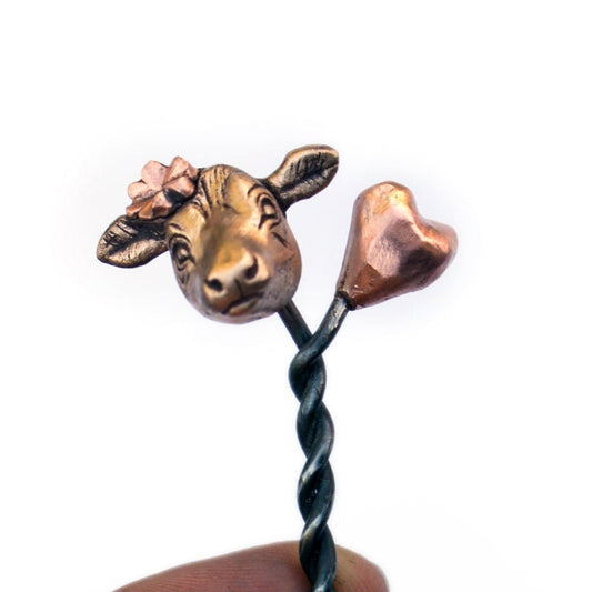 A forged steel hair stick with a sculpted cow head in bronze and copper  on top