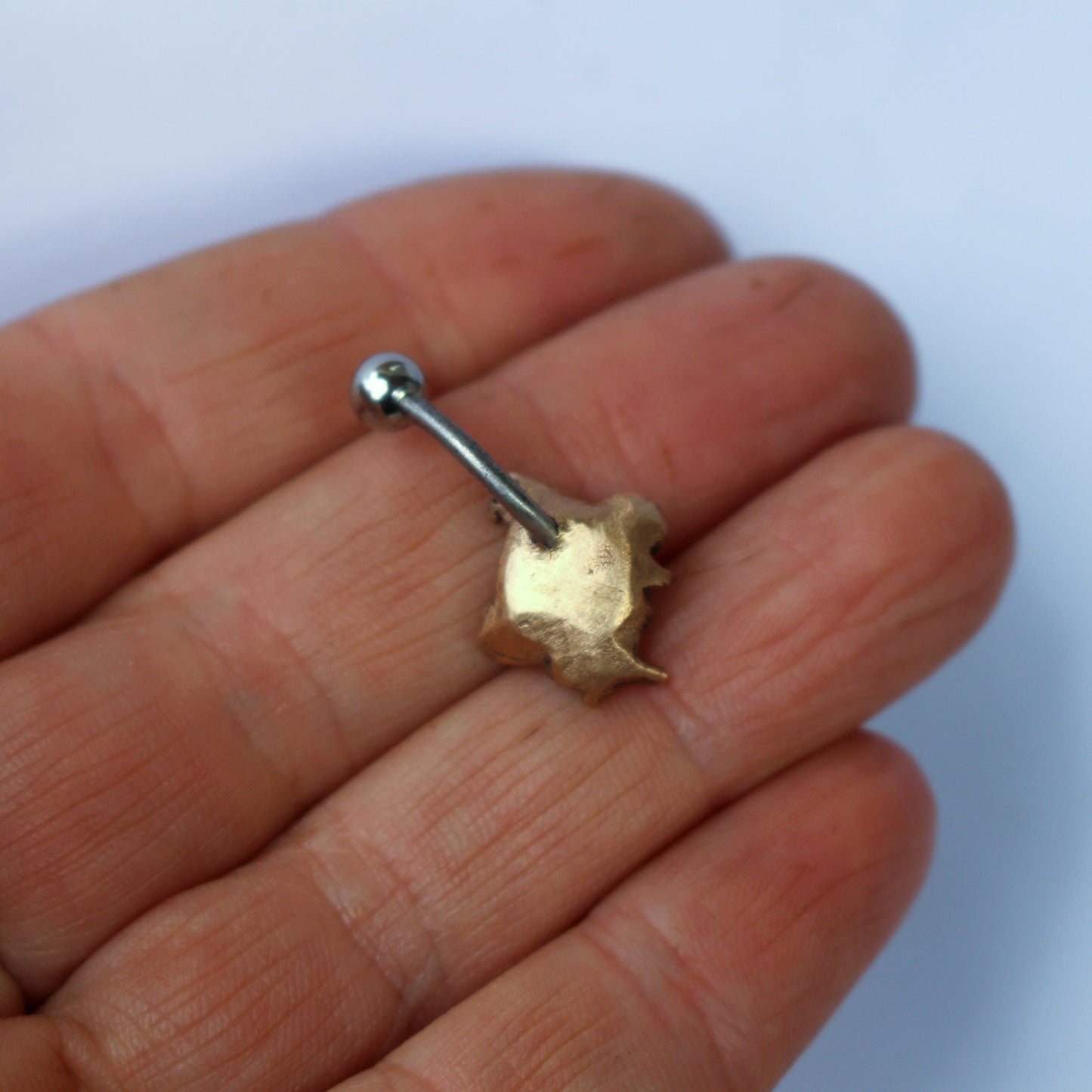 baksida navelpiercing smycke med texten fuck you skulpterat i brons