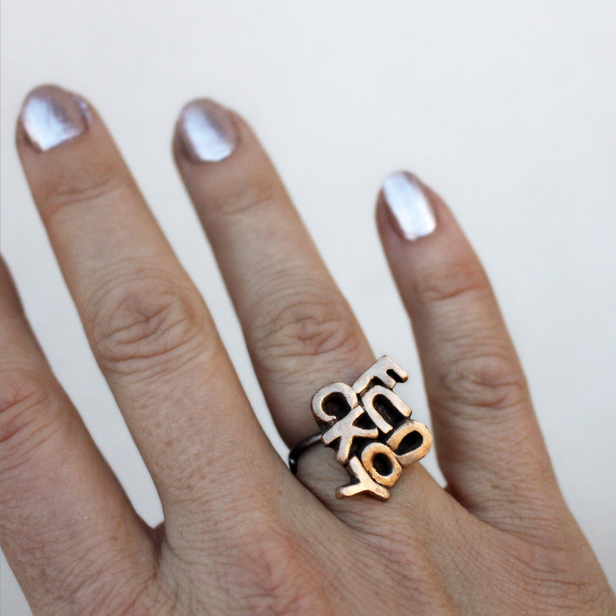This image features a bold and expressive ring, with the phrase "Fuck you" sculpted in bronze letters on the top. The letters are polished to highlight their details, and the bronze is sealed with a durable jewelers lacquer to ensure longevity.