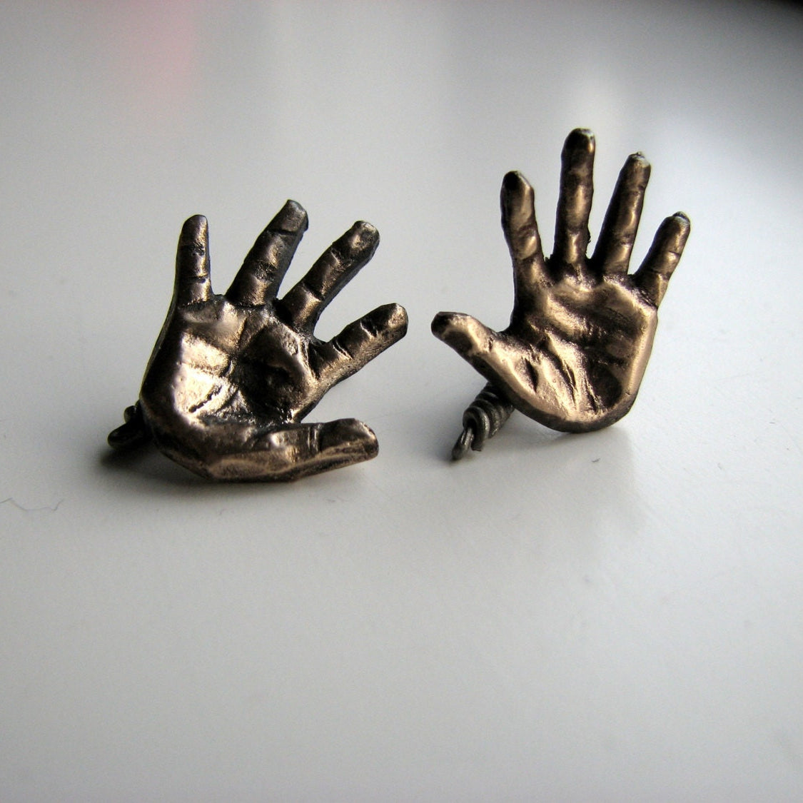 manschettknappar med miniatyr händer skulpterade i brons