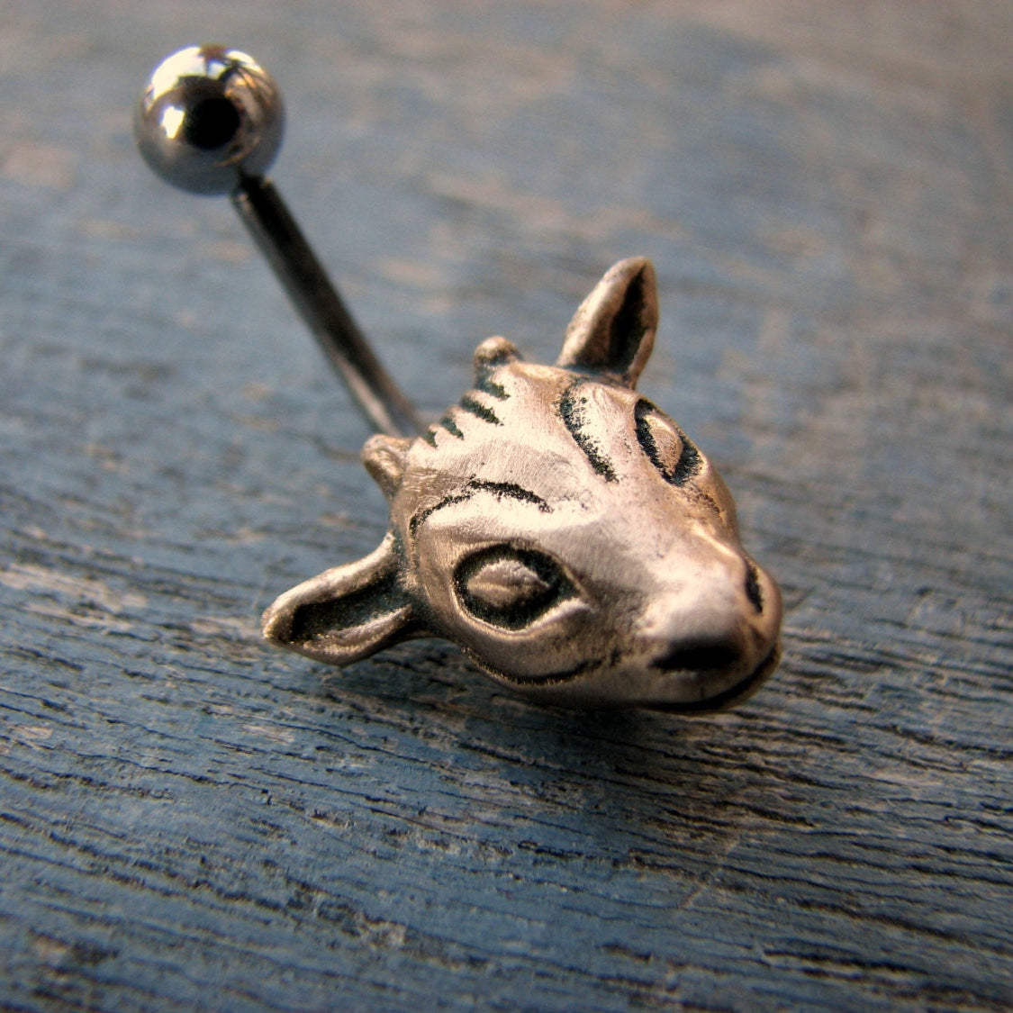 navelpiercingsmycke med ett gethuvud skulpterat i brons, stav i titan eller kirurgiskt stål
