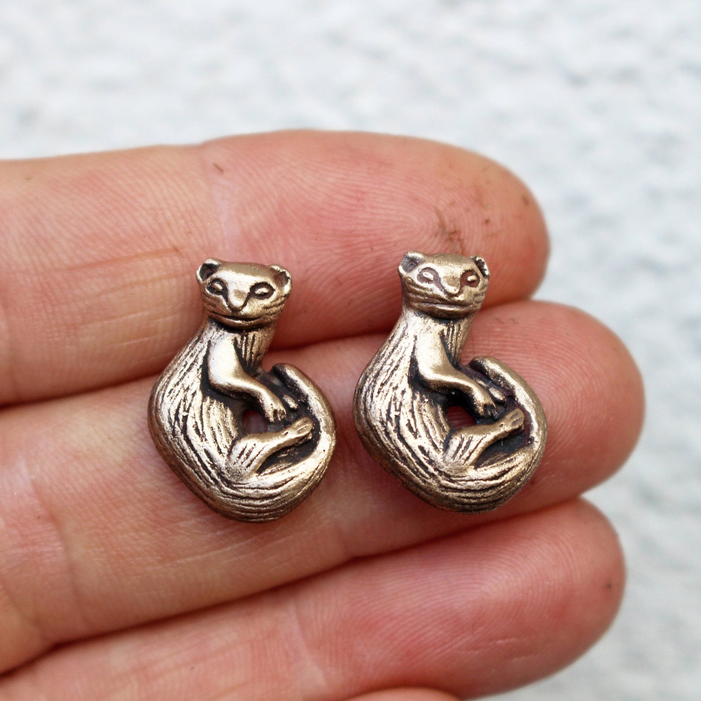 handgjorda iller örhängen i brons och titan hållna i en hand