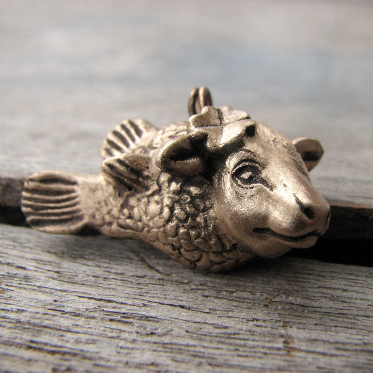 halsband, skulpterat i brons, föreställande en ko med fiskkropp med en fyrklöver bakom ena örat