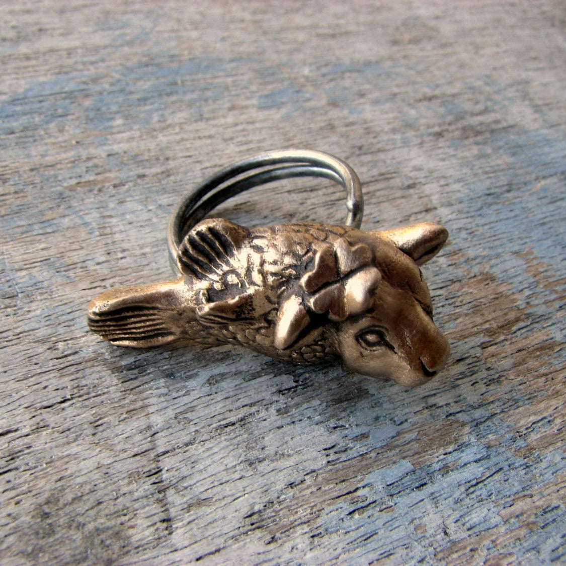 kofisk ring skulpterat i brons, smycke med en ko med fiskkropp med en fyrklöver bakom ena örat