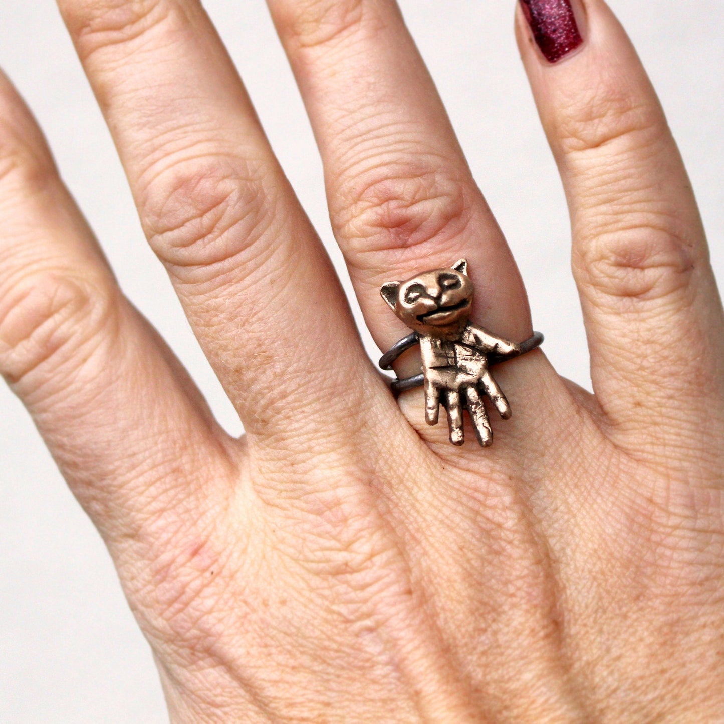 konstig kattring i brons och stål, katt med hand som kropp