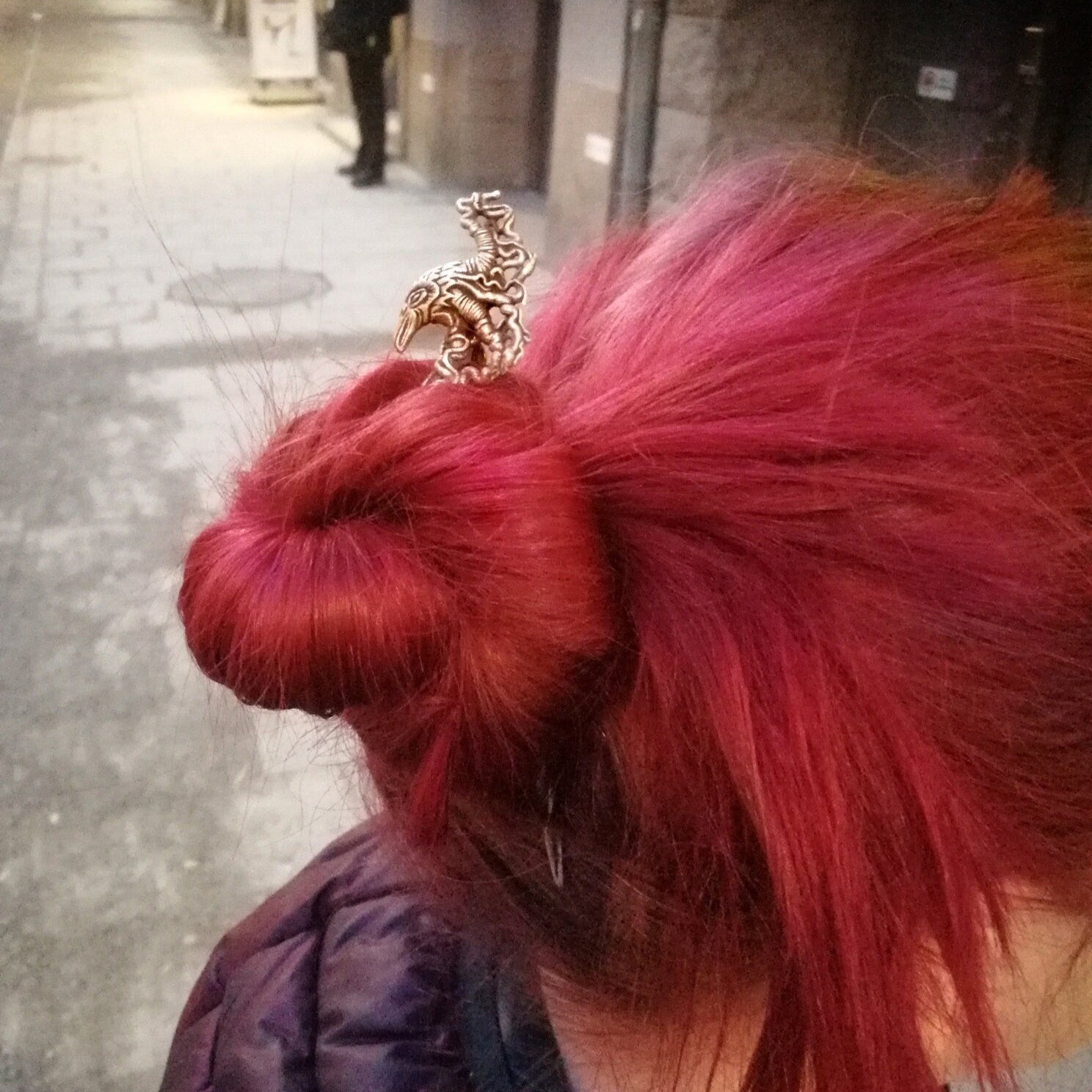 hårsticka med skulpterat korphuvud i brons och smidd pinne av stål på en modell med starkt rött hår