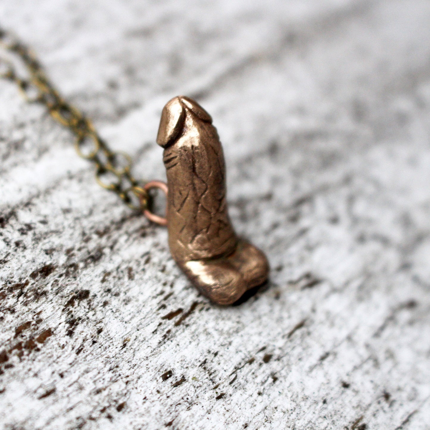 halsband med en erigerad penis skulpterad i brons