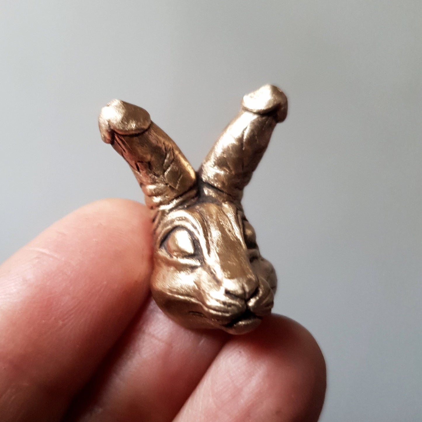kukkanin, miniatyr figur i brons föreställande ett  kaninhuvud med snoppar som öron. Figuren tillverkas som halsband, ring eller brosch