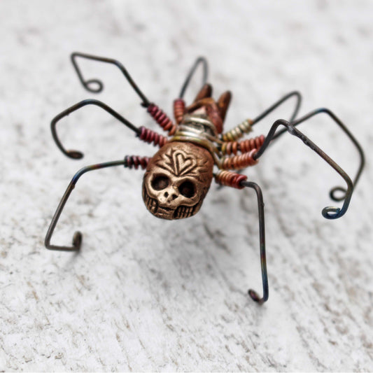 A large skull spider earring with titanium legs and bronze body, wire wrapped and soldered together.