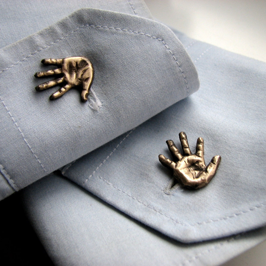 manschettknappar med miniatyr händer skulpterade i brons