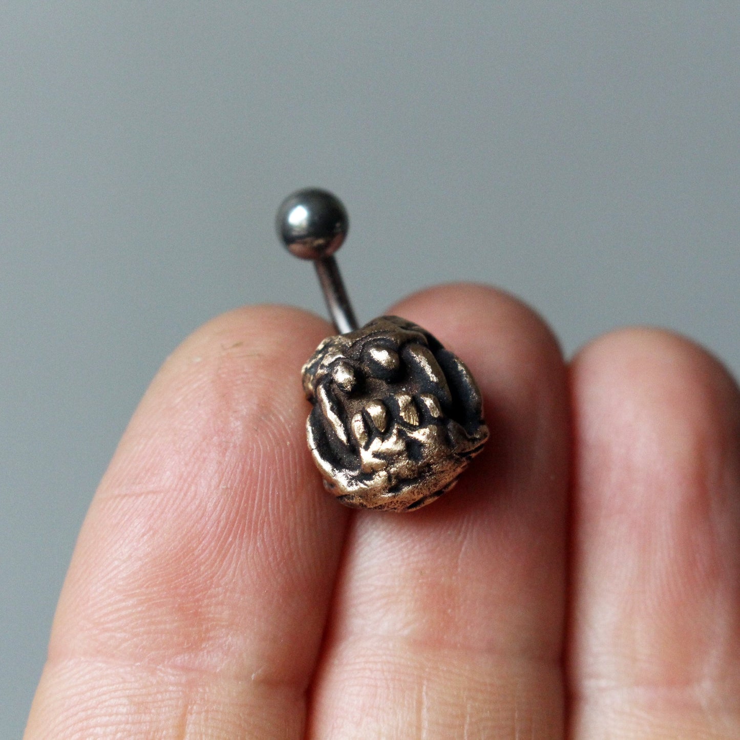 titan navelpiercingsmycke med skulpterade monstergaddar i brons