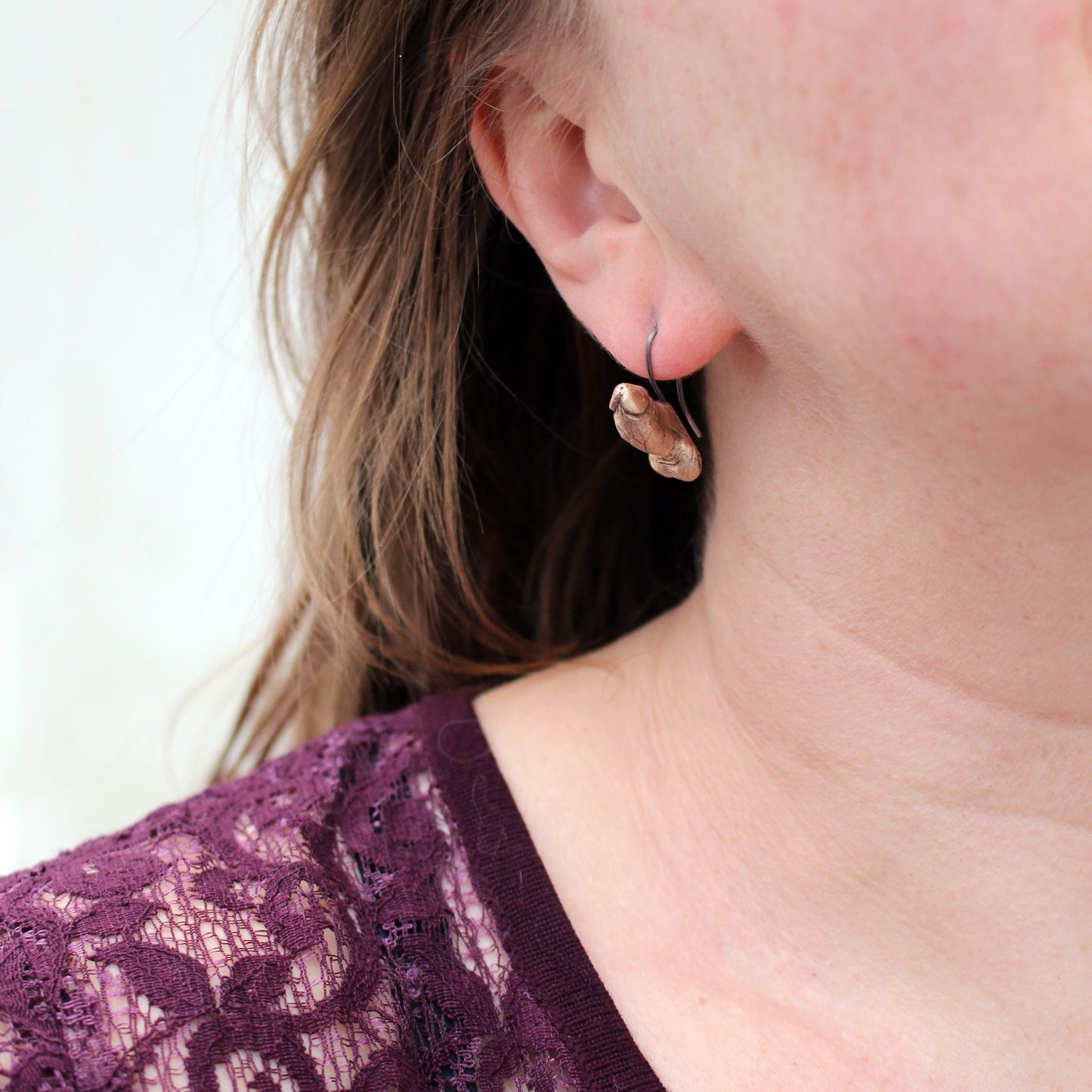 örhängen, med titan krokar, föreställande erigerade kukar skulpterade i brons