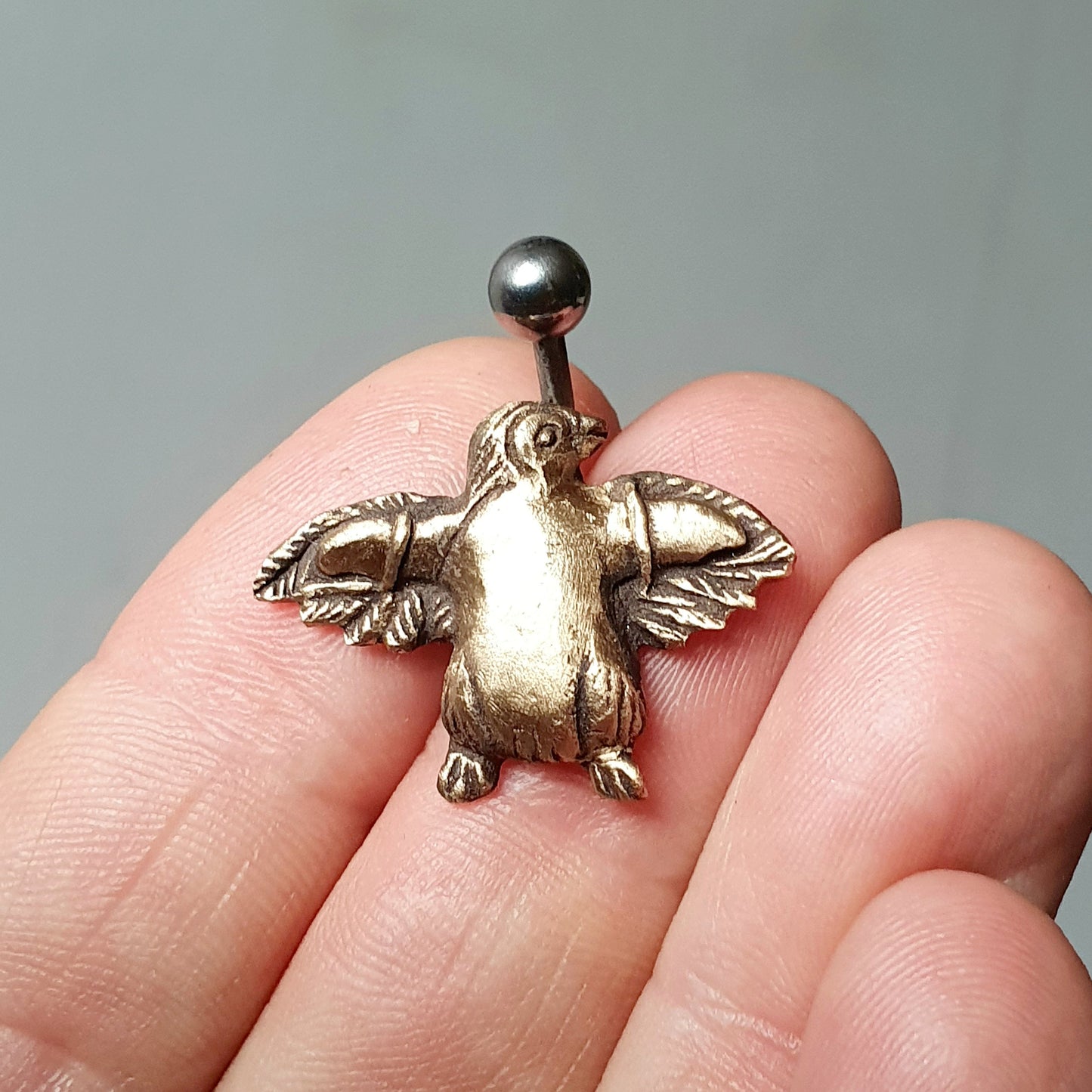 navel piercing smycke med en handgjord brons pingving med lösvingar