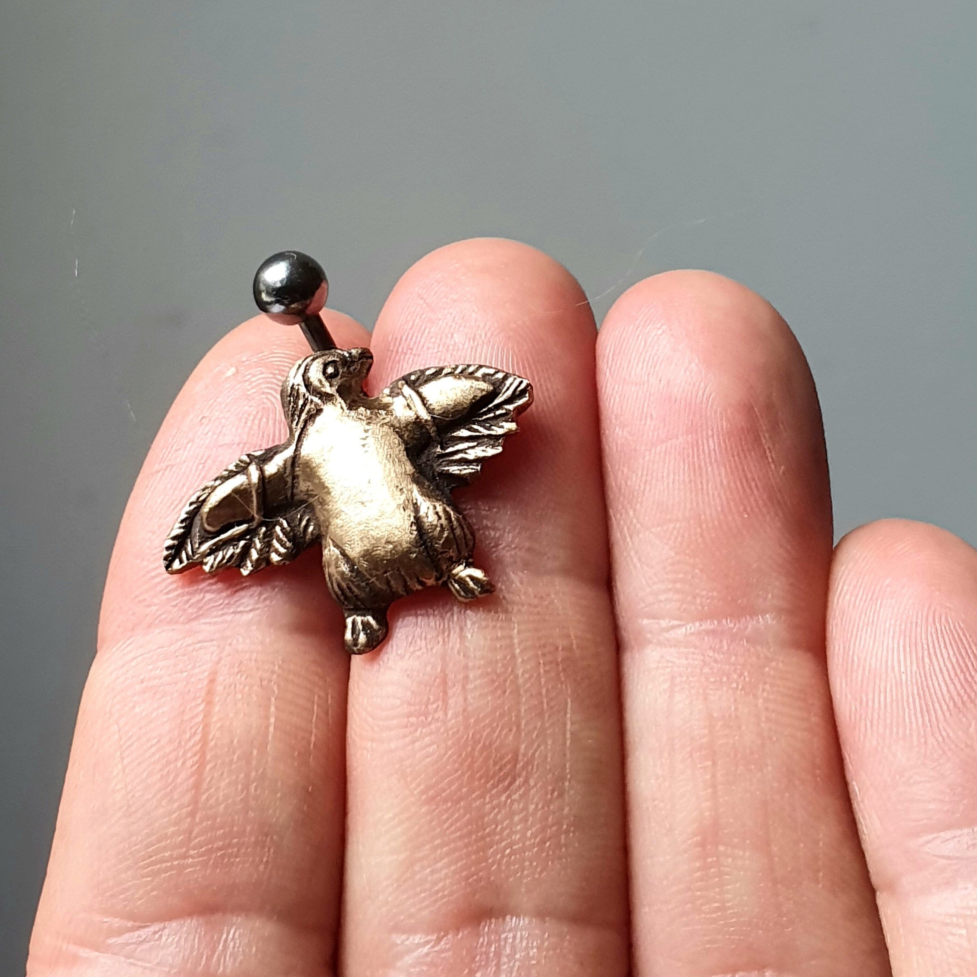 navel piercing smycke med en handgjord brons pingving med lösvingar