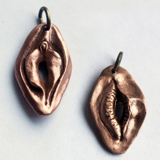 Reversible necklace showing both sides, a mouth on one side and a vulva on the other. The piece is made from either copper or silver