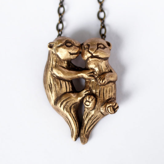 Bronze necklace with two sea otters kissing, held in a embrace, with a chain link.