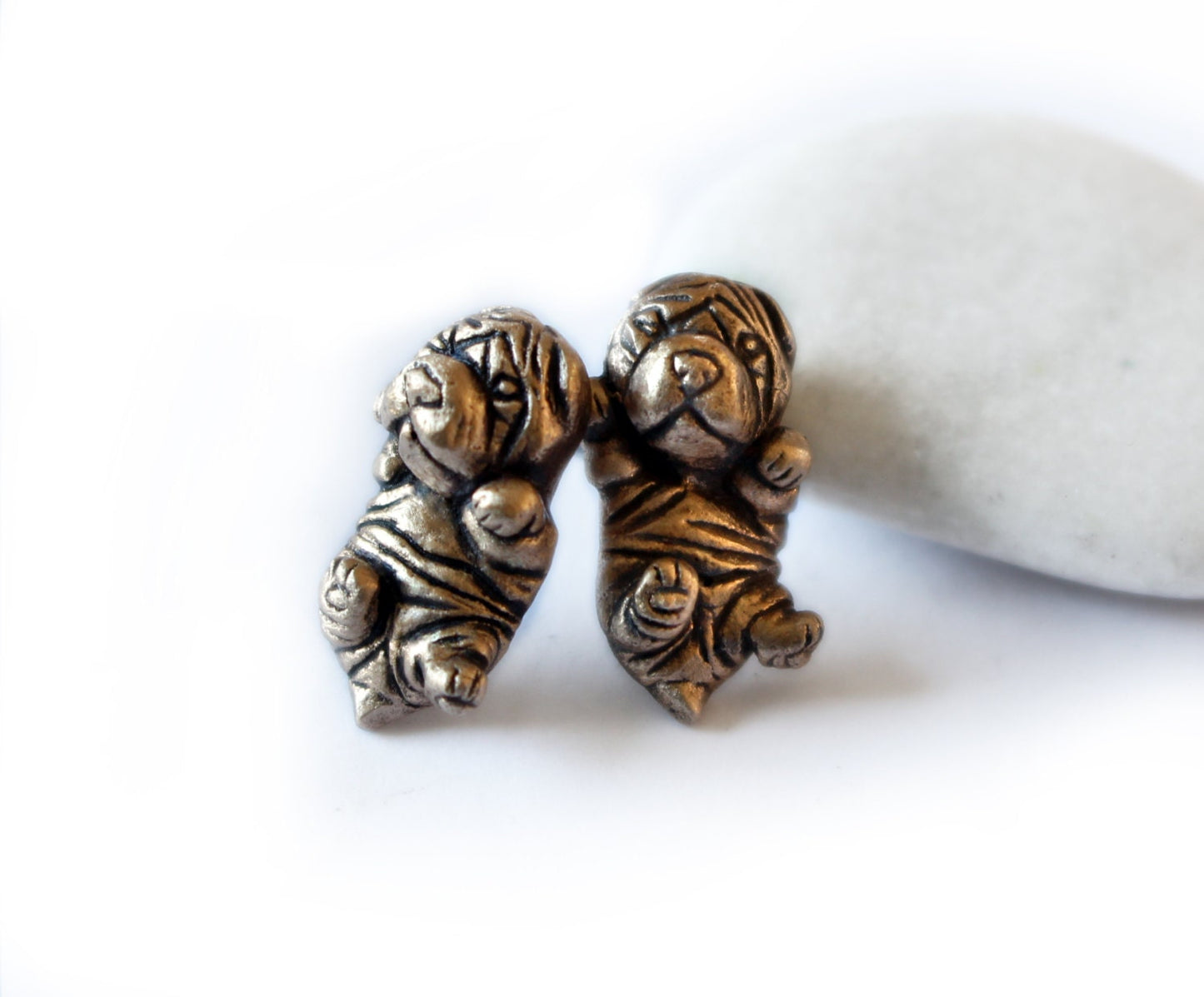 A pair of Shar pei puppy dog earrings made of bronze, displayed against a white background.