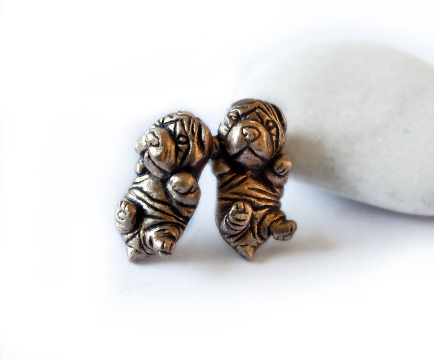 A pair of Shar pei puppy dog earrings made of bronze, displayed against a white background.