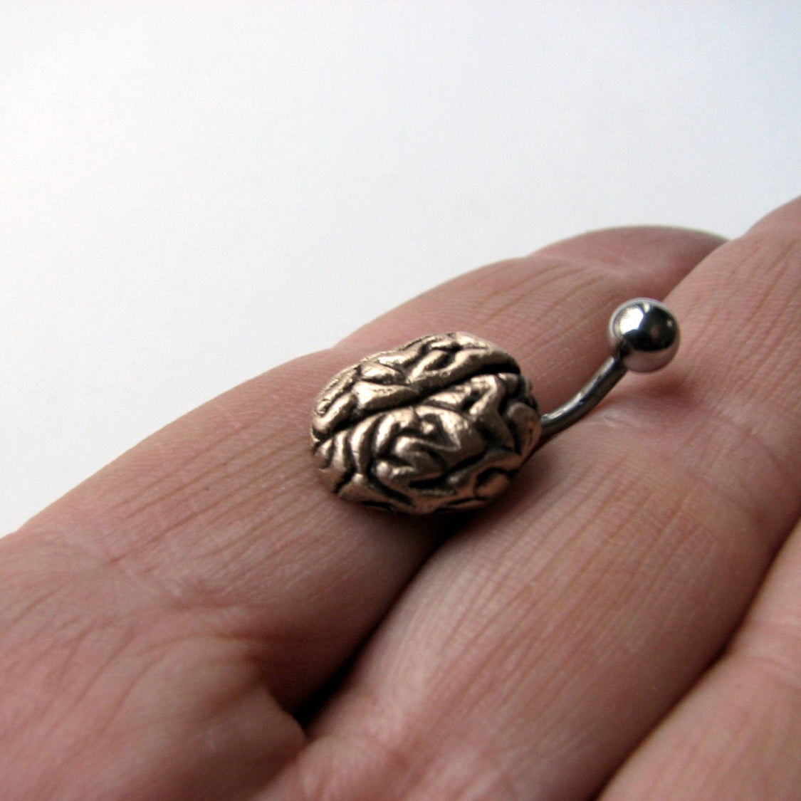 Navelpiercing smycke med en liten skulpterad hjärna i brons och titan stång