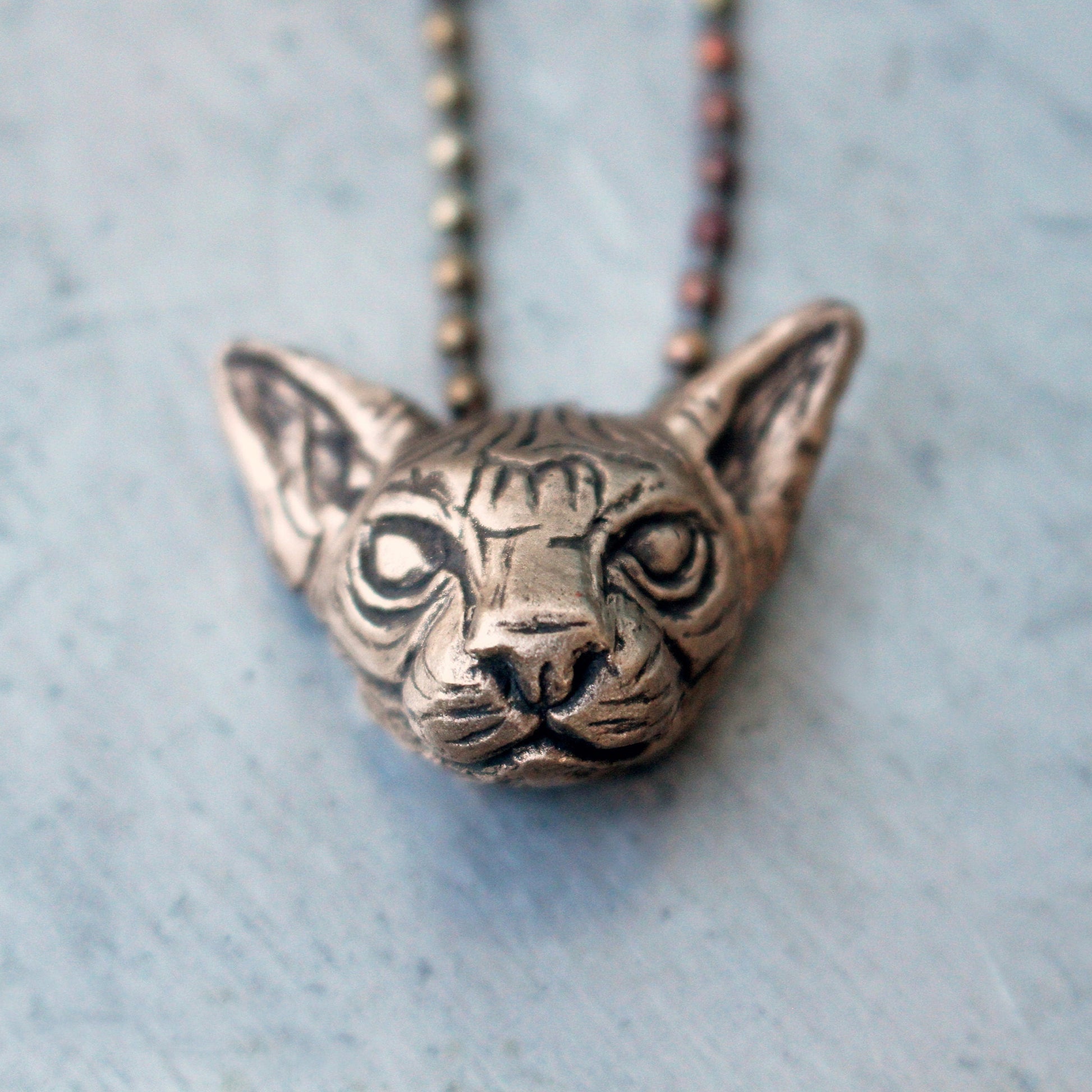 Bronze hairless cat head pendant on a chain 