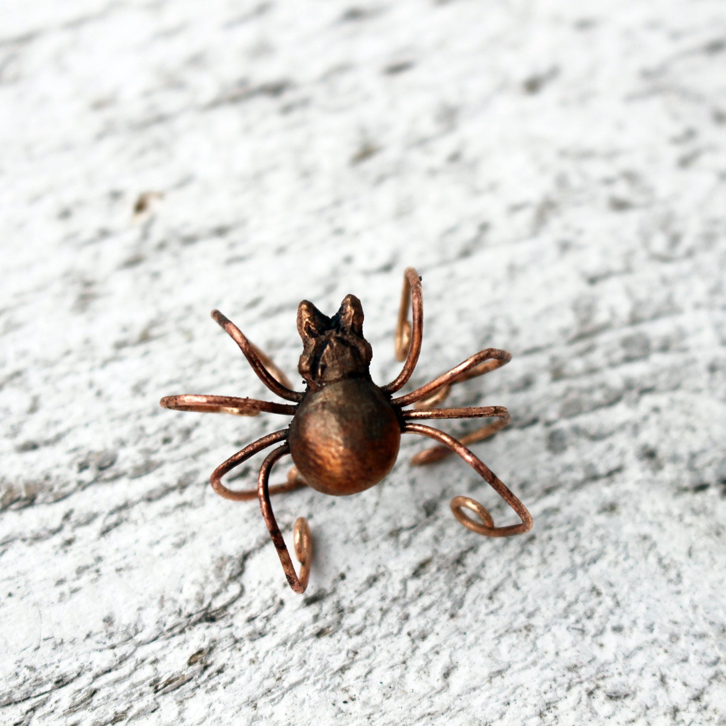spider ear cuff on a white wodden surface