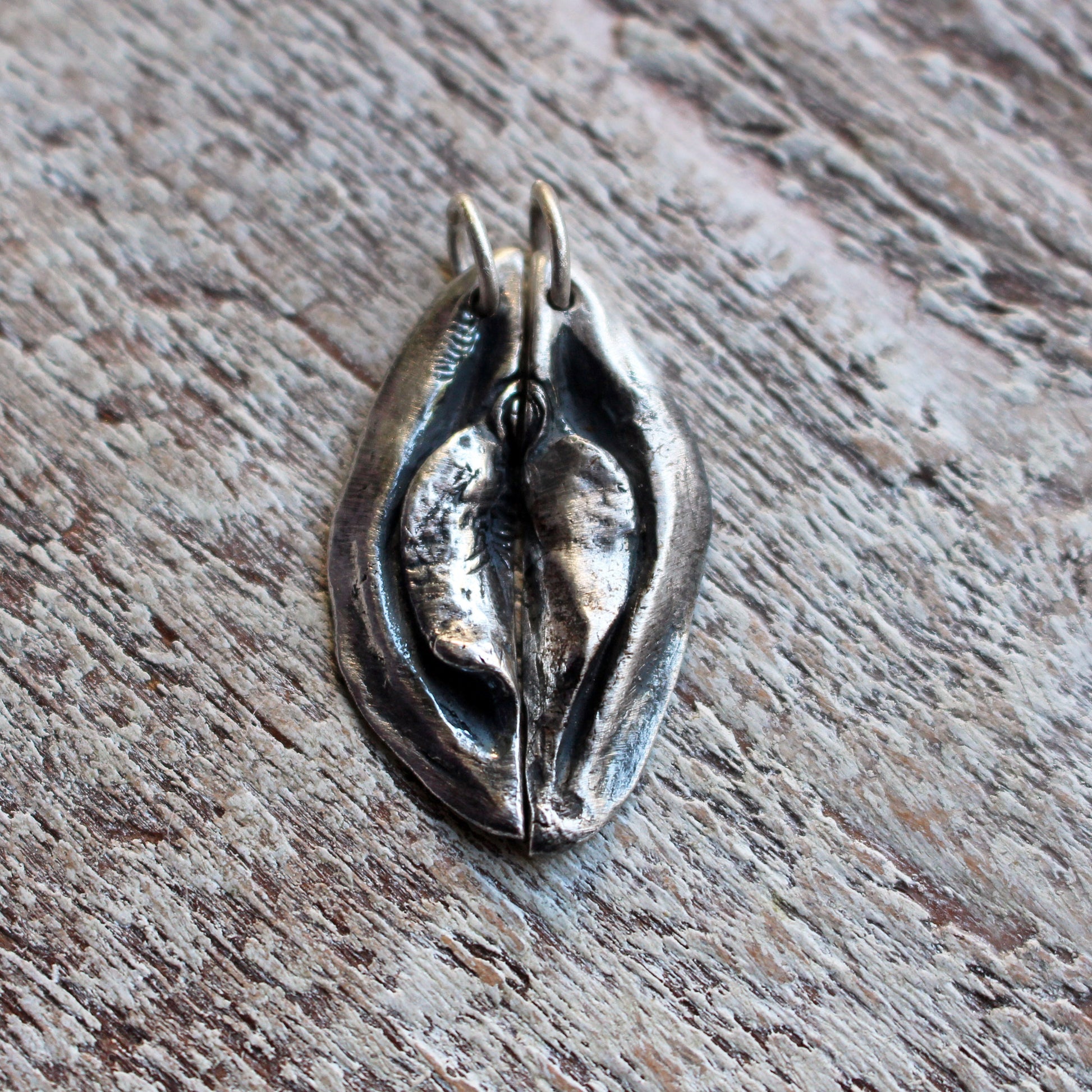 an artistic necklace pendant, designed as a split heart vagina vulva, to share with a lover