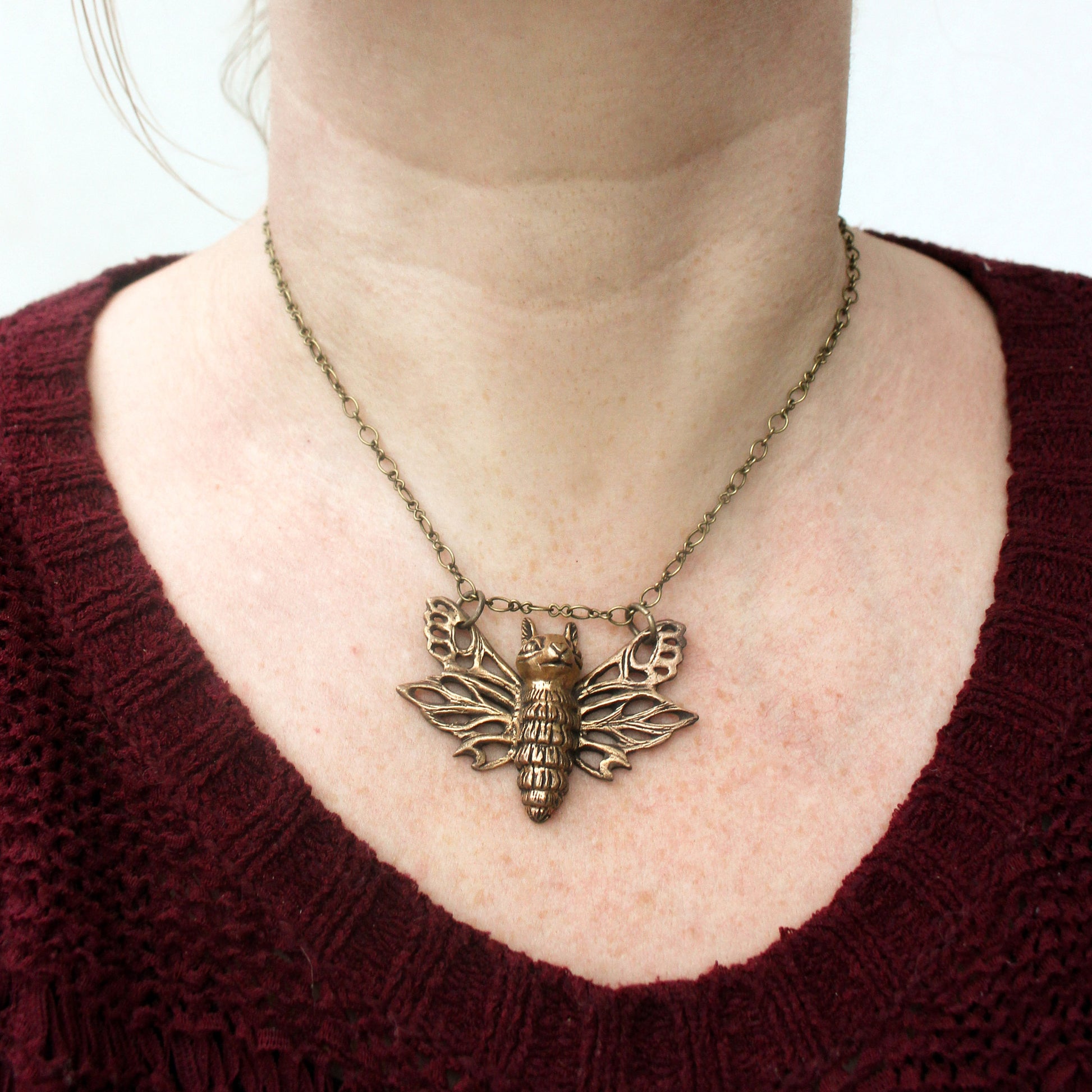 necklace with a cross between a moth and a squirrel, flying squirrel
