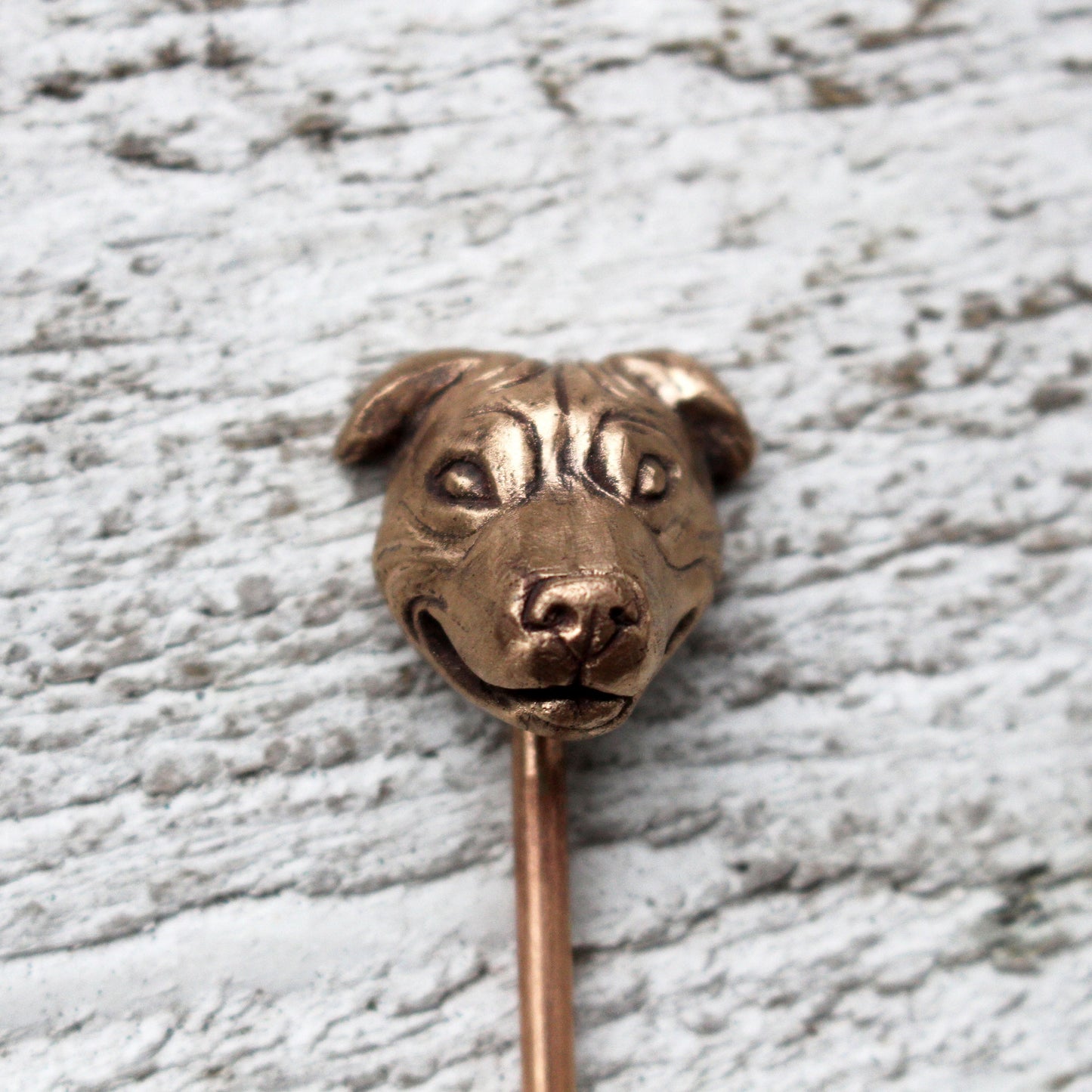 A bronze hairpin with a sculpted dog  (staffordshire bull terrier) head on top,