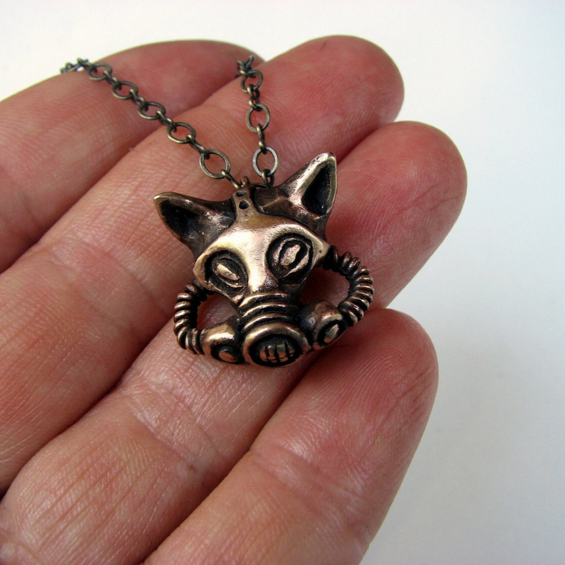 bronze necklace in the shape of a cat wearing a gas mask.