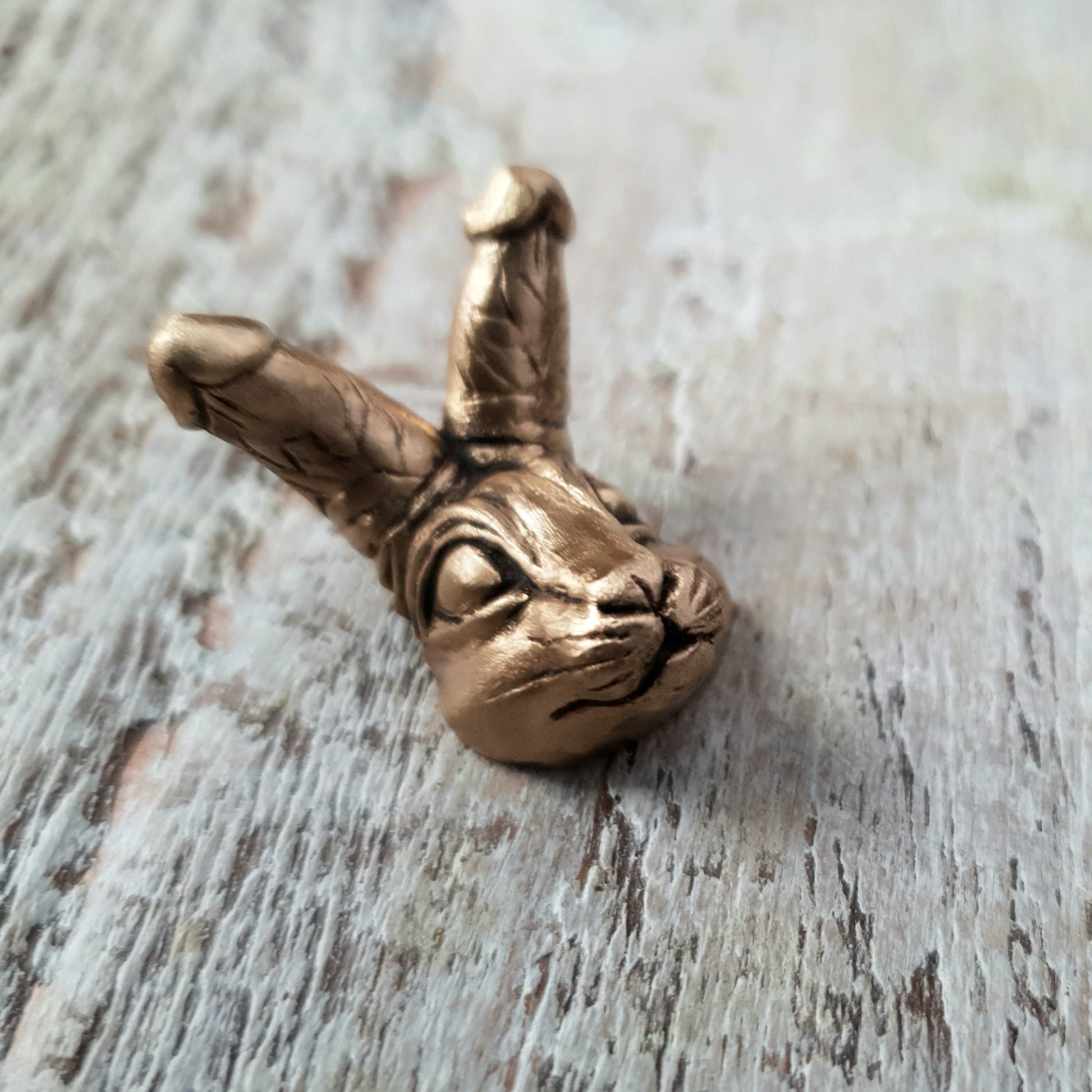 kukkanin, miniatyr figur i brons föreställande ett  kaninhuvud med snoppar som öron. Figuren tillverkas som halsband, ring eller brosch