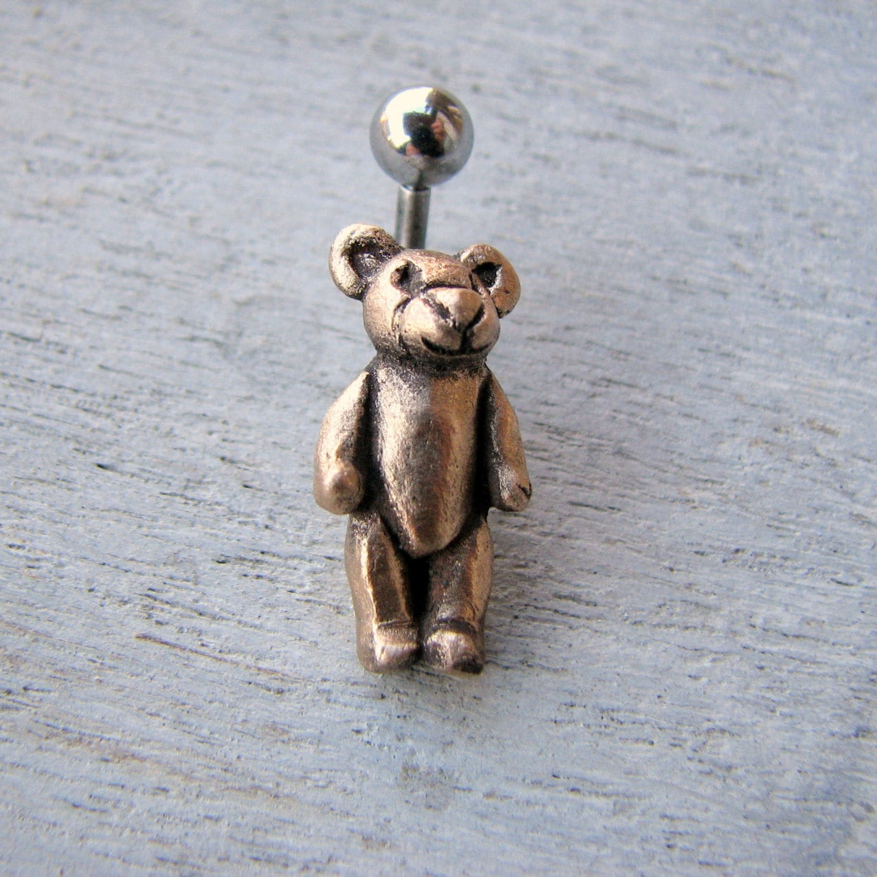 navel piercing smycke i titan eller kirurgiskt stål med en handgjord teddybjörn i brons