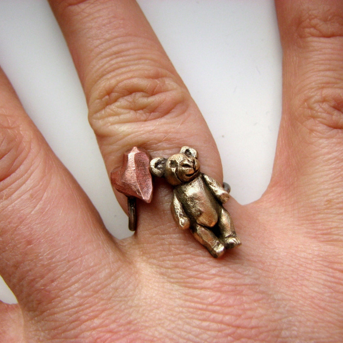 teddybjörn finger ring med en miniatyr nalle och ett hjärta i rosa koppar