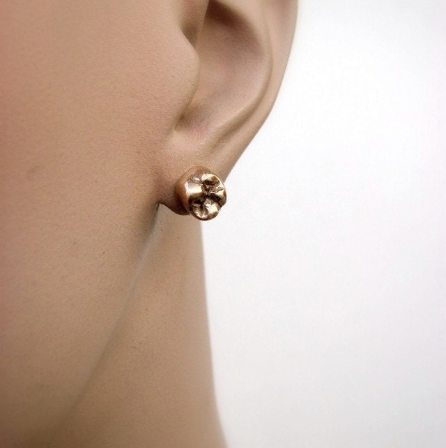 A pair of golde bronze tooth-shaped stud earrings with titanium earwires